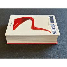 a stack of books sitting on top of a black table next to a white and red book