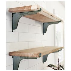 two wooden shelves with metal brackets on the top and one shelf above them, against a white tiled wall