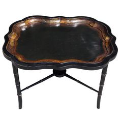 an ornate black and gold tray with metal legs