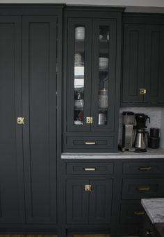 a kitchen with black cabinets and marble counter tops, gold trim on the doors is shown