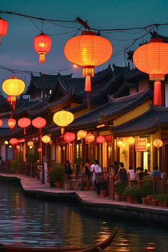 many lanterns are hanging over the water in front of some buildings with boats on it