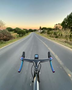 a view from the front of a bike looking down an empty road with trees in the background