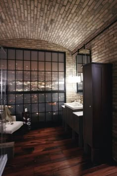 a bathroom with brick walls and flooring next to a window that has glass panes