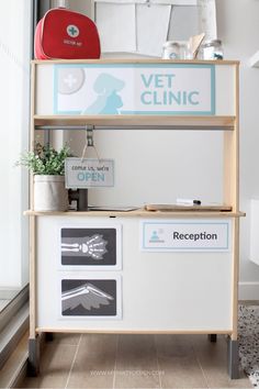 a white and blue vet clinic counter with signs on the front, above it is a potted plant