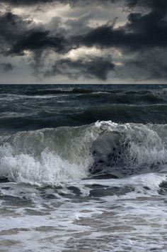 an ocean with waves and dark clouds in the sky