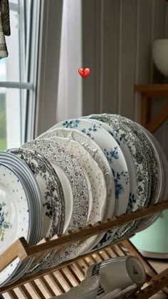 there are many plates on the rack in this room and one red heart is above them