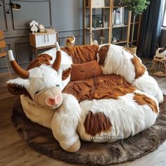 a large stuffed cow laying on top of a round chair in a living room next to a window