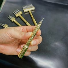 a person is holding five gold colored toothbrushes in their hand and there are other tools on the table