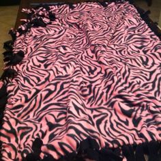 a pink and black zebra print table cloth with tassels on the edge, sitting on a tile floor