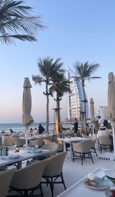 an outdoor dining area overlooking the ocean with palm trees