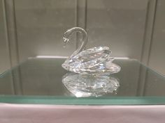 a crystal swan sculpture sitting on top of a glass table