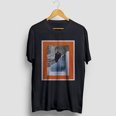 a black t - shirt with an orange border on the front and bottom, featuring a photo of a bear