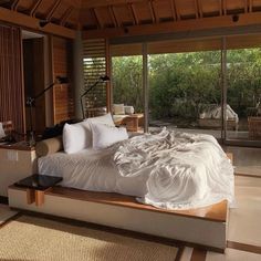 a large bed sitting in the middle of a bedroom next to a window with sliding glass doors