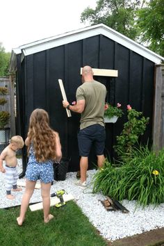 a man and two children are working on a shed