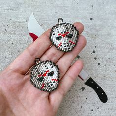 a hand holding two beaded earrings in the shape of a cat with red eyes