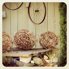 three wooden balls sitting on top of a table next to some rocks and plants in front of a wall