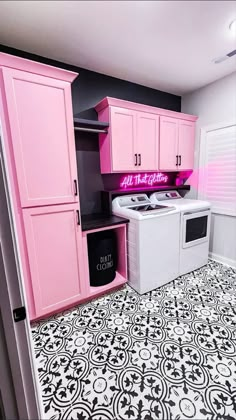 a pink kitchen with black and white flooring, cabinets, and an all - in - one washer and dryer