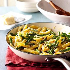 a pan filled with pasta and asparagus on top of a table