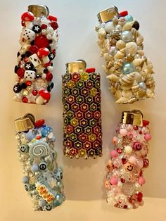 four cell phones are lined up on a white surface with beads and charms attached to them