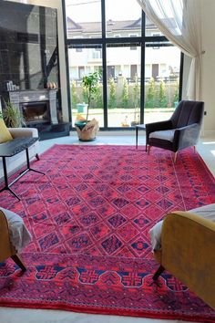 a living room filled with furniture and a red rug