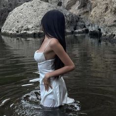 a woman standing in the water wearing a white dress