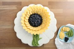 a cake made to look like a sunflower with grapes and cheese on it next to a plate of fruit