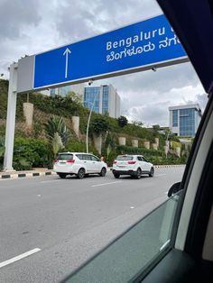 two cars are driving down the road under a blue sign