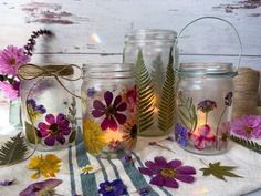 three glass jars with flowers painted on them are sitting on a striped towel and some twine