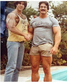 two men standing next to each other near a pool