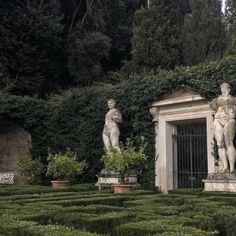 two statues in the middle of a garden