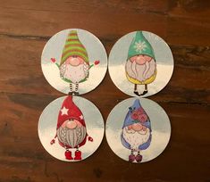 four christmas gnome coasters sitting on top of a wooden table