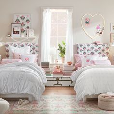 two beds in a room with pink and white decor on the walls, one has a heart shaped window