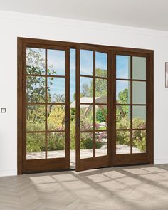 an empty room with wooden floors and sliding glass doors that lead to a large garden