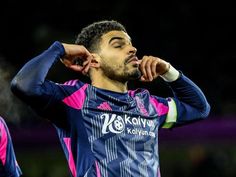 a soccer player with his head in his hands looking up at the sky and holding his hand to his ear