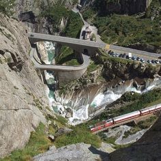 a train traveling over a bridge on top of a rocky cliff next to a river