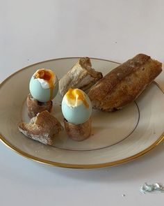 an egg is sitting in the middle of some bread on a white and gold plate