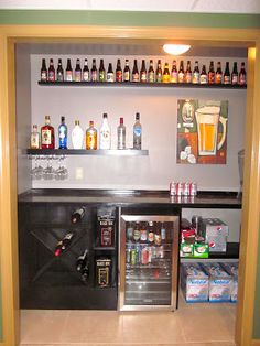 a small bar with lots of bottles and cans on the shelves, along with an ice chest