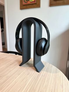 a pair of black headphones sitting on top of a wooden table next to a wall