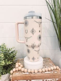 a coffee cup sitting on top of a wooden table next to a potted plant