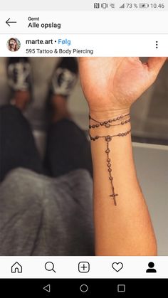 a person with a tattoo on their arm holding up a cross and rosary bracelets