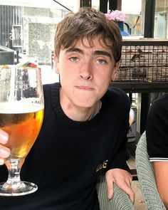 a young man holding up a glass of beer