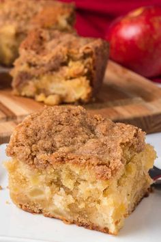 a close up of a piece of cake on a plate with an apple in the background