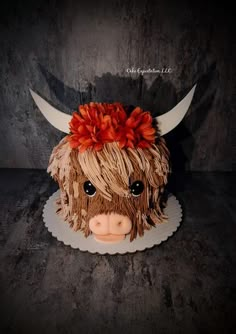 a ceramic cow head with red flowers on it's hair and horns is shown in front of a dark background