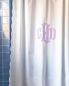 the monogrammed shower curtain in this bathroom is white and has purple letters on it