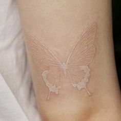 a small white butterfly tattoo on the side of a woman's right leg,