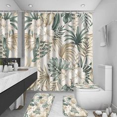 a bathroom with a toilet, sink and bathtub covered in tropical print shower curtain