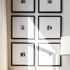 four black and white framed pictures hang on the wall next to a table with a lamp