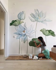 a woman sitting on the floor painting a mural