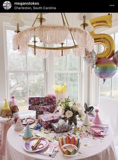 a table is set with balloons, plates and confetti