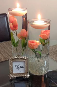 two vases filled with flowers on top of a table next to a candle holder